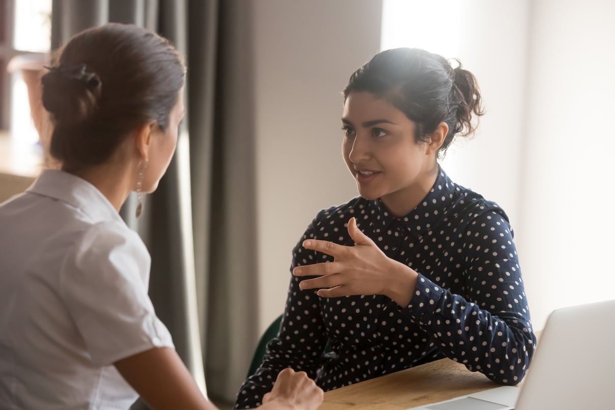 Serious indian mentor worker talk to female colleague teach intern